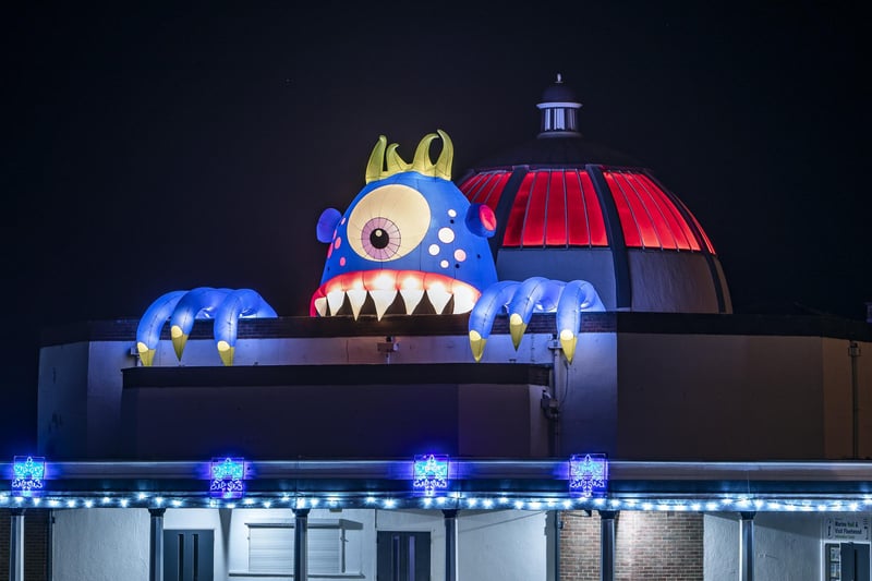 Chomper, a giant monster, peering from the illuminated roof of Marine Hall