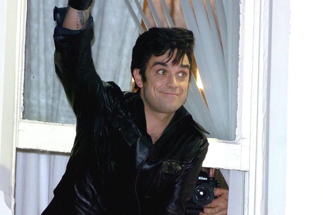 Robbie Williams leaning out of a window at the Belle Vue Hotel in Whitegate Drive, waving to fans in the street below in 2005