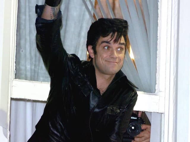 Robbie Williams leaning out of a window at the Belle Vue Hotel in Whitegate Drive, waving to fans in the street below in 2005