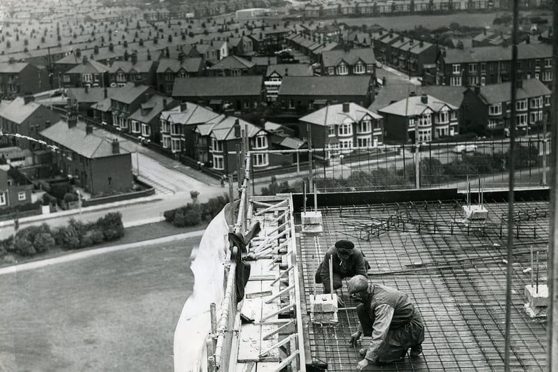 Men working on the new high rise flats at Queenstown, Layton. Cumbrian Avenue joins Mather Street which runs left to right across the centre. The spire of Layton Hill Convent School (now St Mary's High School) can be seen in the distance to the left. The open ground of Kingscote playing fields can be seen top right