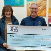 Dave Whitwoth, from DWS Support Services, with two choir members from Encore Singers at the presentation of a cheque for £565.