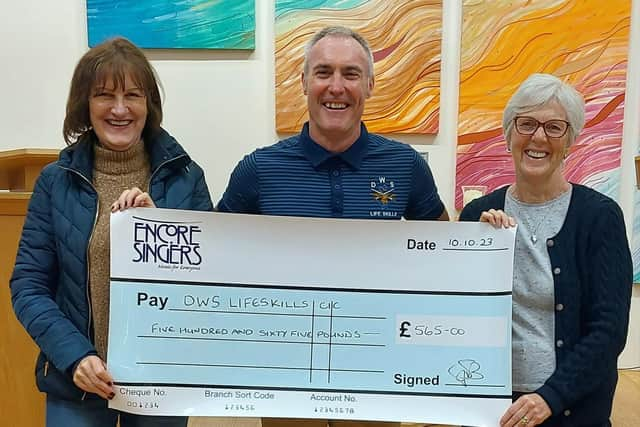 Dave Whitwoth, from DWS Support Services, with two choir members from Encore Singers at the presentation of a cheque for £565.