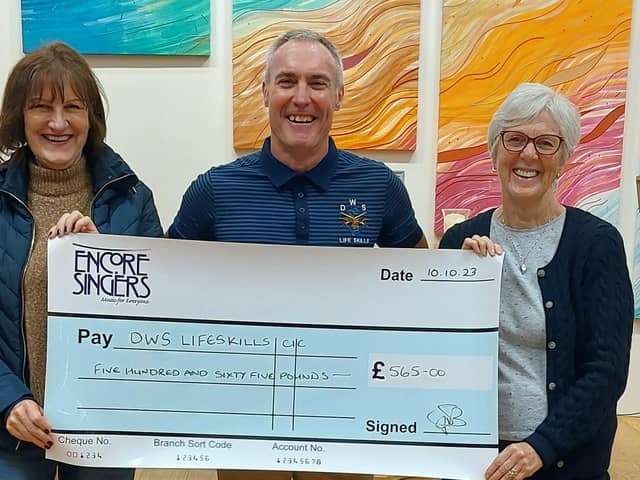 Dave Whitwoth, from DWS Support Services, with two choir members from Encore Singers at the presentation of a cheque for £565.
