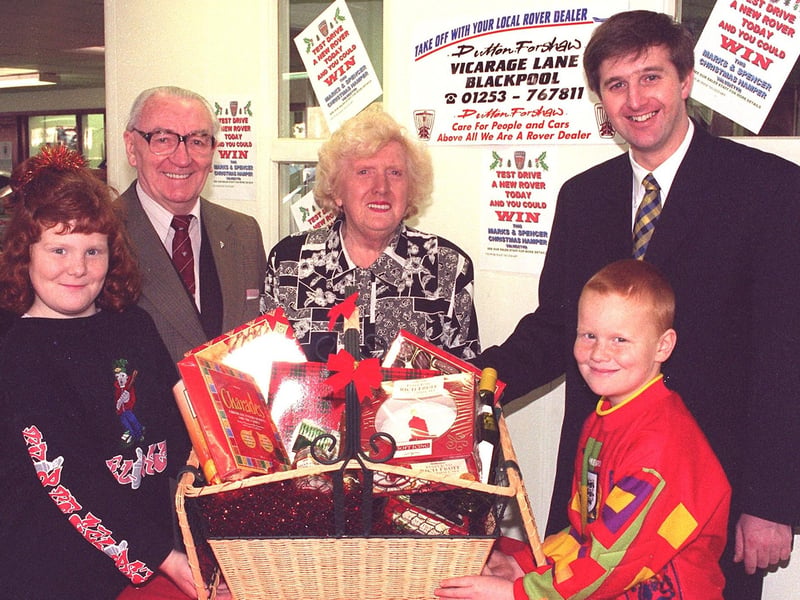 Maurice and Joyce Eastwood, of Daggers Hall Lane receive their Marks and Spencer Christmas Hamper from Dutton Forshaw service manager Keith Warrilow, at the Dutton Forshaw Vicarage Lane premises. Helping them to carry it are grandchildren Deyna and Arran Hall