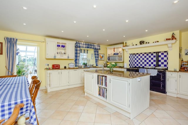 The central breakfast kitchen has a range of wall and base units including a large central island, granite worktops, Belfast sink and a four-oven Aga.