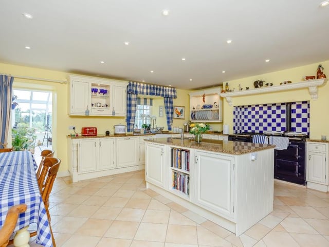 The central breakfast kitchen has a range of wall and base units including a large central island, granite worktops, Belfast sink and a four-oven Aga.