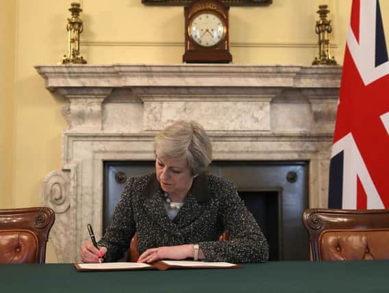 Prime Minister Theresa May singing the letter to trigger Article 50