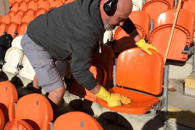 Fan Dave WIggins scrubs four years of grime and pigeon muck off the seats at Bloomfield Road