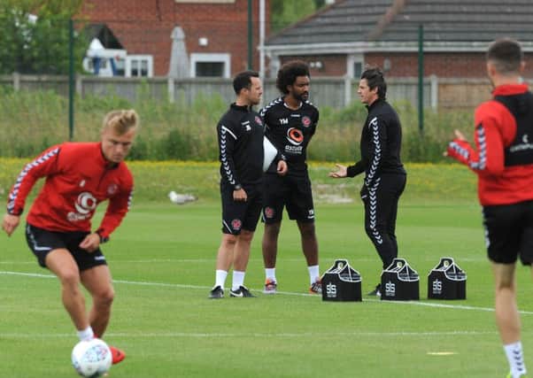 New Fleetwood Town head coach Joey Barton talks to sports scientists Youl Mawene and James Barrow as Kyle Dempsey trains