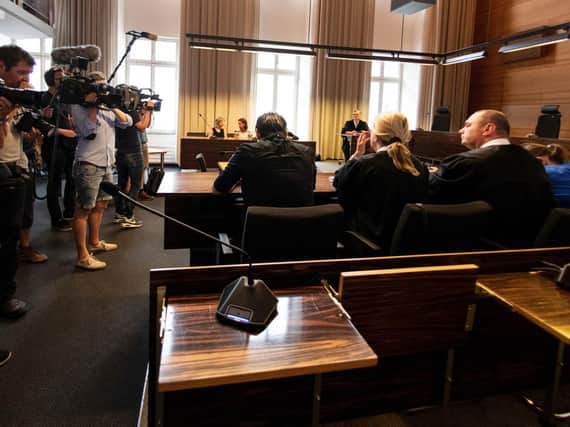 Photographers take pictures of the a man and a woman in the court in Freiburg, southern Germany, Tuesday, Aug. 7, 2018 before they were sentenced to long-term prison sentence for for offering the 9-year-old son of the woman for raping by pedophiles. (Patrick Seeger/dpa via AP)