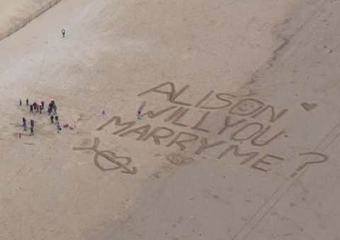 Pilot Thomas Bennett proposed to his girlfriend Alison Moul mid-flight with a giant message written in the sand below