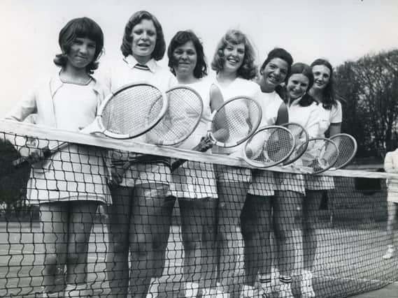 'Half-a-dozen young lady members of Poultons Moorland club, in 1974, all dressed charmingly in fashionably short, white tennis skirts or shorts, holding wooden Dunlop-Maxply racquets and ready at the net for a fresh season.'