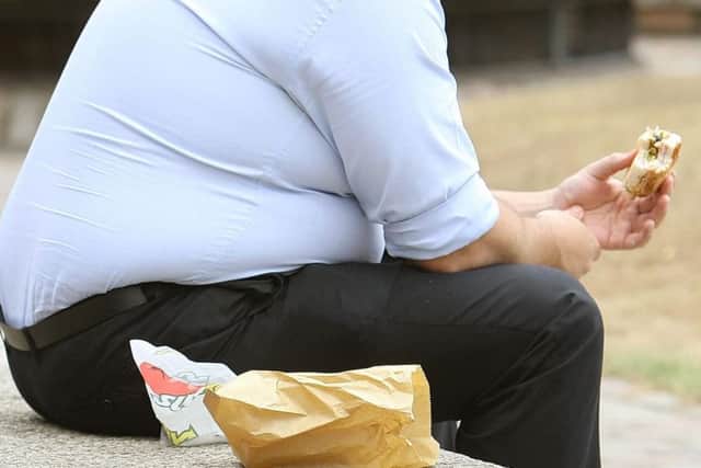 Stock image of an overweight man eating fast food (Picture: Dominic Lipinski/PA Wire)