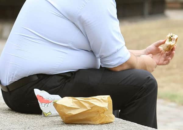 Stock image of an overweight man eating fast food (Picture: Dominic Lipinski/PA Wire)