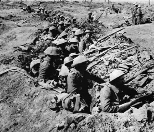 British infantrymen occupying a shallow trench in a ruined landscape before an advance during the Battle of the Somme