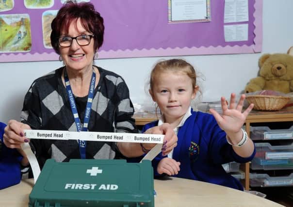 Mereside Primary has introduced a wristband system for pupils who bang their head.  Megan Blackburn, six, with pastoral manager Lesley Lawrence.