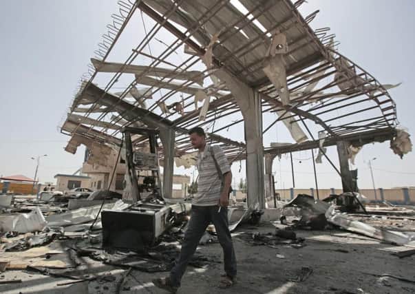A Yemeni man walks on the rubble of a petrol station after it was hit by Saudi-led airstrikes in Sanaa, Yemen, this year