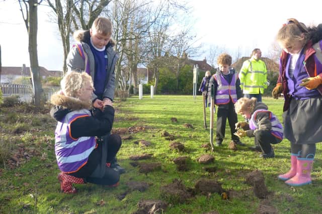 Youngsters fill the holes that have been dug with spring bulbs at Gateside Park