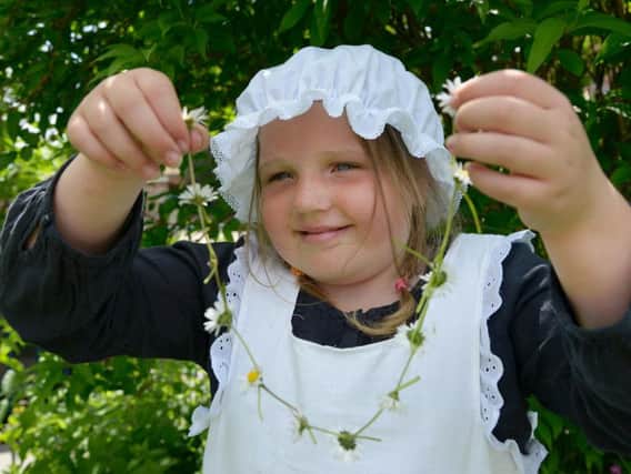 A girl making a daisy chain, an activity the National Trust thinks children should do by the age of 12