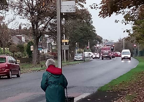A woman waits for a bus on busy Poulton Road, where residents say elderly people are struggling to reach the post office, which is based inside the garage