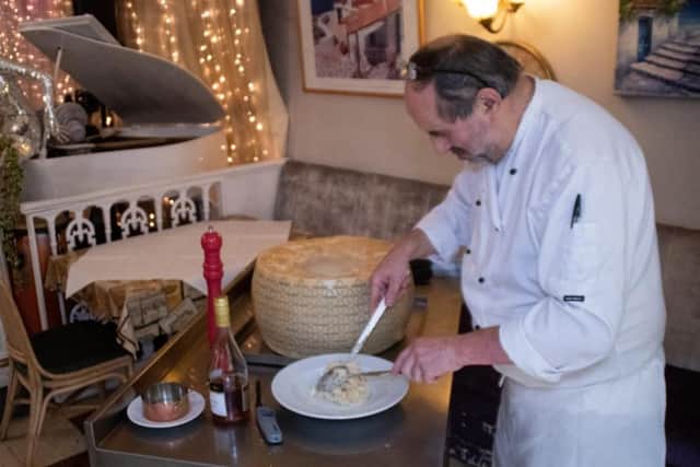 Chef Alain serving pasta from the cheese wheel