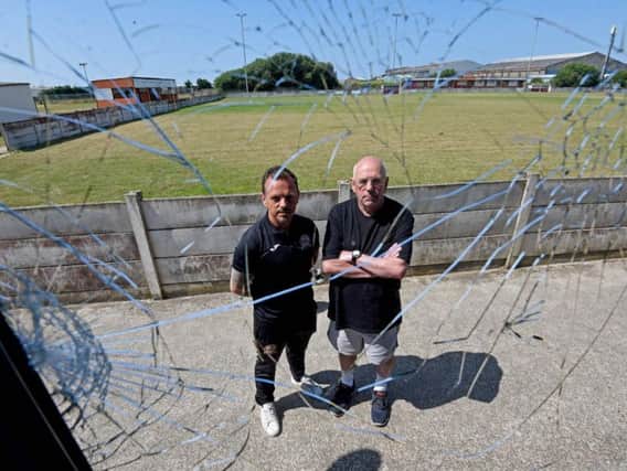 Club welfare officer Justin Singleton with club secretary Billy Singleton, pictured through a window which was smashed by vandals