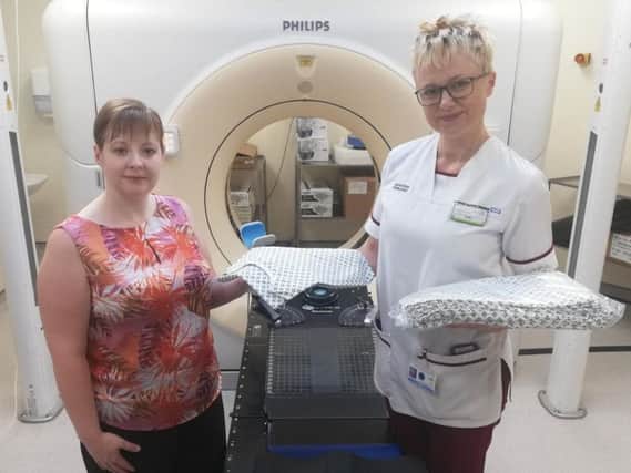 Treatment delivery team Leader Kelly Littlefair (right) hands over the radiotherapy departments stock of new Rosemere Cancer Foundation funded gowns to treatment planning team leader Catherine Abbott