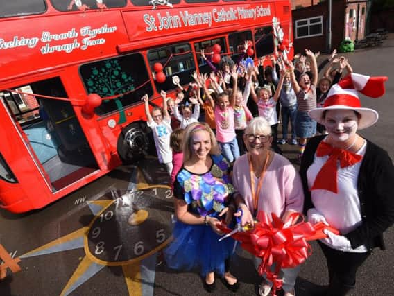 Staff and pupils at St John Vianney's Primary School celebrate the opening of their new library bus. Reading leader Tessa Dickinson, acting chair of governors Liz Boniface and deputy headteacher Clare Evans cut the ribbon to open the bus.
