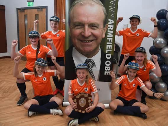 The successful Year Seven girls football team (now in Year Eight) with their trophy, wearing some of Jimmy Armfield's Englad caps at Armfield Academy