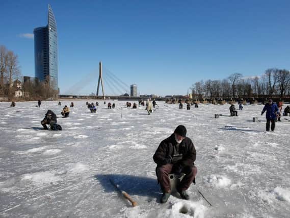 A general view of fishermen on the frozen ice of the Daugava River with the Shroud Bridge or Vansu tilts in the background on March 22, 2013 in Riga, Latvia. (Photo by Dean Mouhtaropoulos/Getty Images)