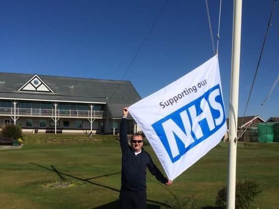 Knott End chairman David Weir raises the NHS flag outside the club