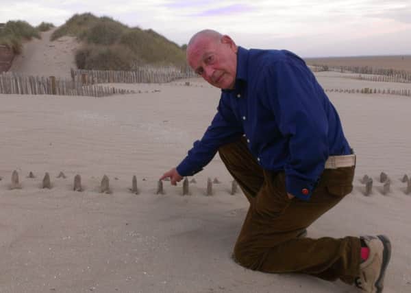 Resident Dr Brian Newman near a section of the fence left protruding from the sand.