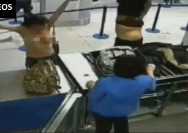 Two women strip at Manchester Airport security.