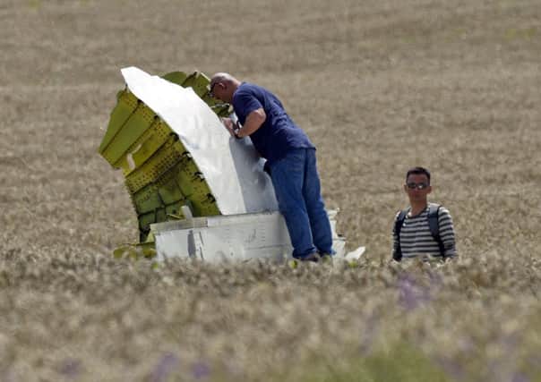 Tragic loss:  Malaysian air crash investigators take pictures of wreckage at the crash site of Malaysia Airlines Flight MH17 near the village of Hrabove, eastern Ukraine, yesterday. Below - Glenn Thomas from South Shore, who was killed in the tragedy