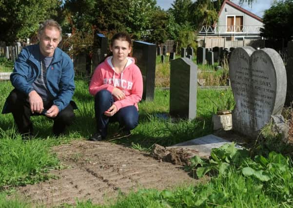 John Davies-Allen was horrified when he visited the grave of his grandparents and mother in Thornton's Christ Church graveyard and found the headstone covered in dirt and digger tracks across the grave. John and his daughter Natasha examine the damage.  PIC BY ROB LOCK 28-8-2014
