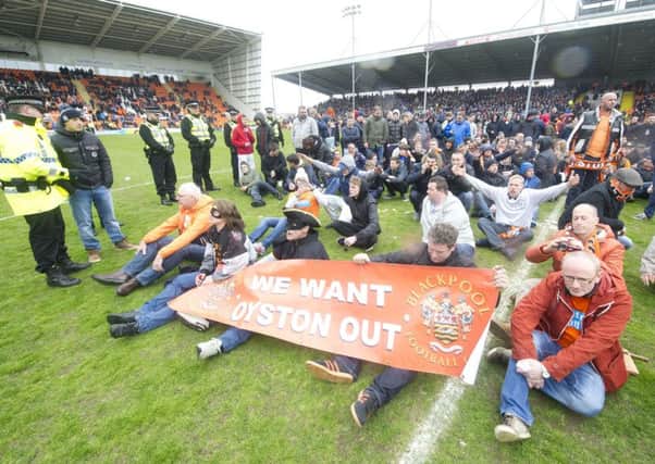 Supporters sit in the centre circle after invading the Bloomfield Road pitch. The game was eventually abandoned