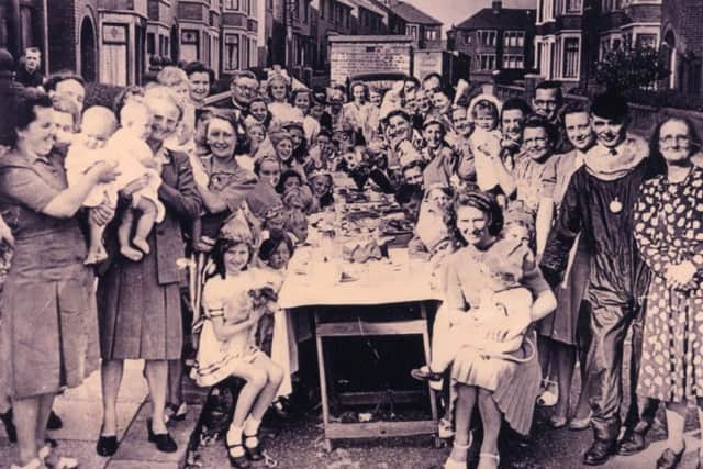 VE Day in Thirsk Grove, Blackpool where young and old celebrate with a street party.  Note the air raid shelters in the background. Historical World War Two.