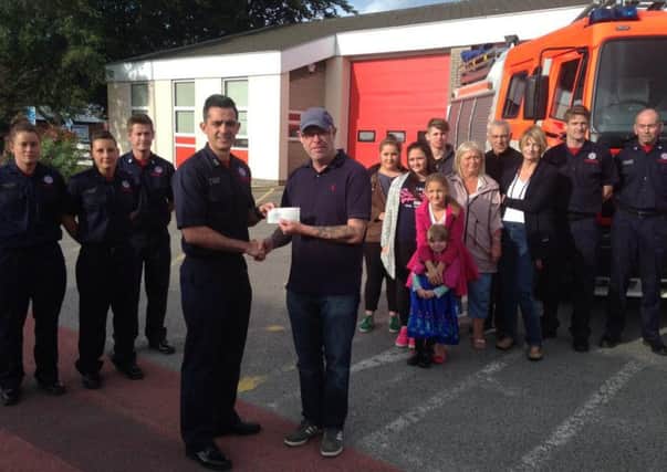Paul Dosset, 42, hands over a cheque for more than £1,600 to firefighters at Lytham Fire Station after his skydive