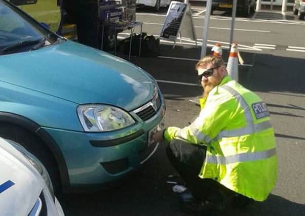 PCSO Paul Parkes fixes anti-theft screws to a number plate in Fleetwood.