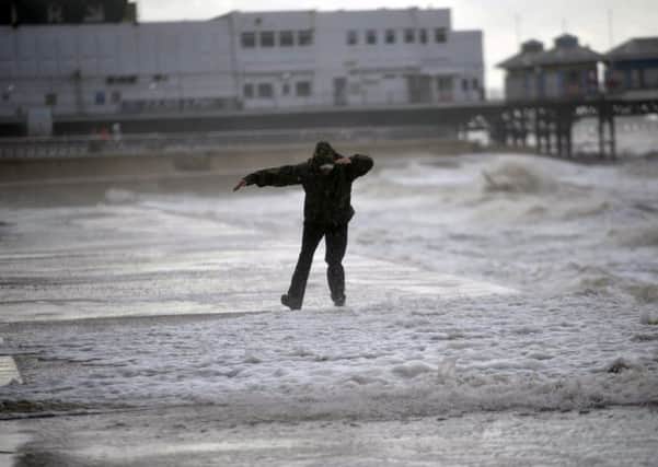 A man gets soaked by waves whilst walking along the promenade of Blackpool