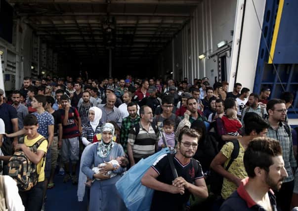 Migrants and refugees disembark from a ferry