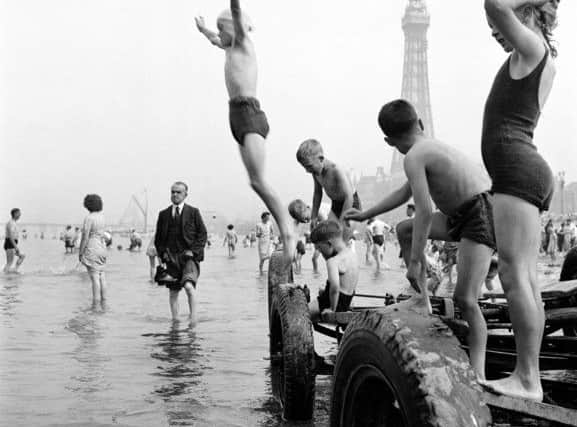 General view of a group of children jumping from a boat trailer at the waters edge with people paddling and blackpool tower in background Lancashire Blackpool Blackpool Memories book published by True North Books