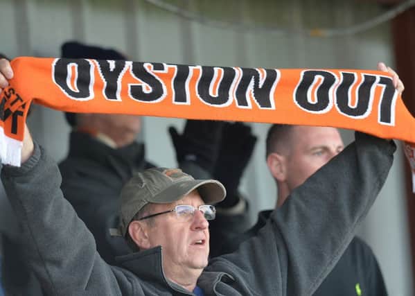 A Blackpool fan holds up his protest scarf at Fleetwood last week