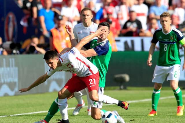 Poland's Bartosz Kapustka and Northern Ireland's Conor McLaughlin (centre) clash as they battle for the ball. PIC: PA