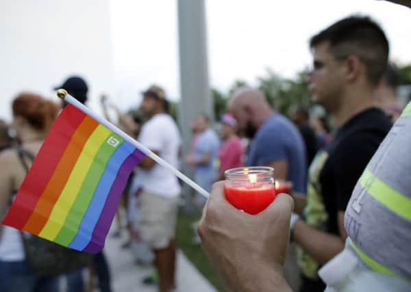 A man holds a candle and a rainbow flag during a vigil in memory of the victims of the Orlando mass shooting, in Miami Beach (AP)