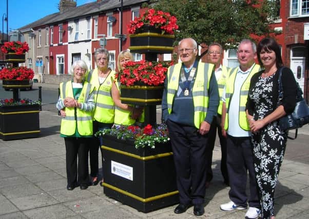 Members of Fleetwood and Cleveleys Lions with Fleetwood Town Council's community development officer, Dawn Spooner, and floral displays in the town.