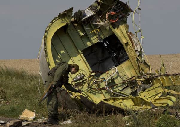 A pro-Russian rebel touches the MH17 wreckage at the crash site.