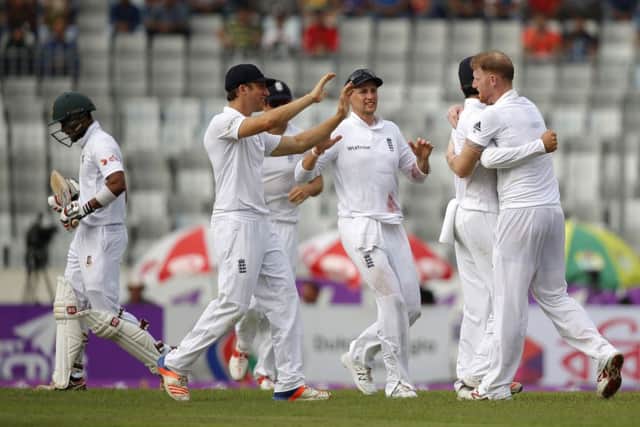 England's Ben Stokes, right, celebrates with his teammates after the dismissal of Bangladesh's Sabbir Rahman, left.