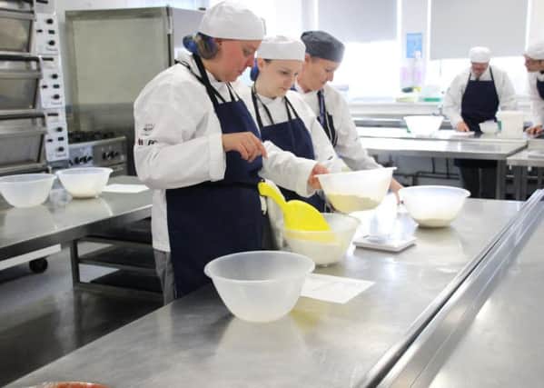 Tutor Carol Davies (right) oversees two students as they weigh out flour.