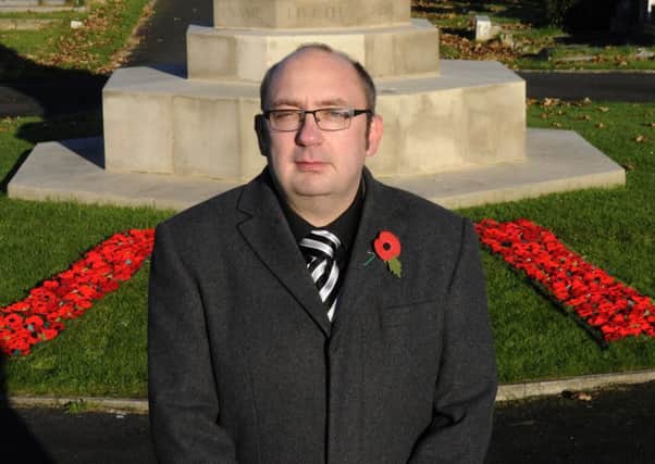 Knitted poppies at the war memorial in Layton Cemetery.  Pictured is Nigel Robinson-Wright.